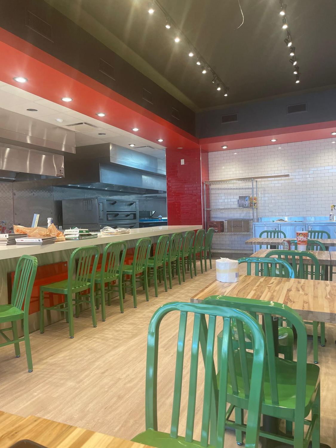 Finished fast casual dining area with green chairs and a butcher block counter rail